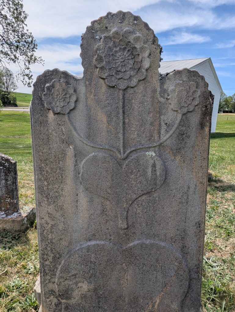 The Flohr footstone carved by Krone — three stylized sunflowers on straight stems rising from a heart